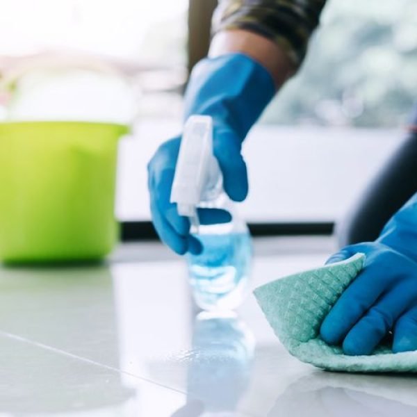 Husband housekeeping and cleaning concept, Happy young man in blue rubber gloves wiping dust using a spray and a duster while cleaning on floor at home.